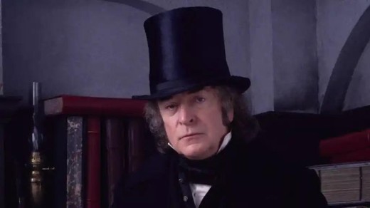 A screenshot of A Muppet Christmas Carol, showing Michael Caine as Ebeneezer Scrooge, wearing a 19th century day coat and a very tall top hat.
